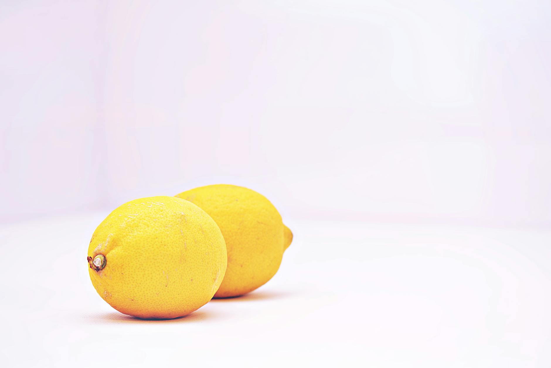 Two vibrant lemons on a clean white background symbolizing fresh starts and renewed pleasure