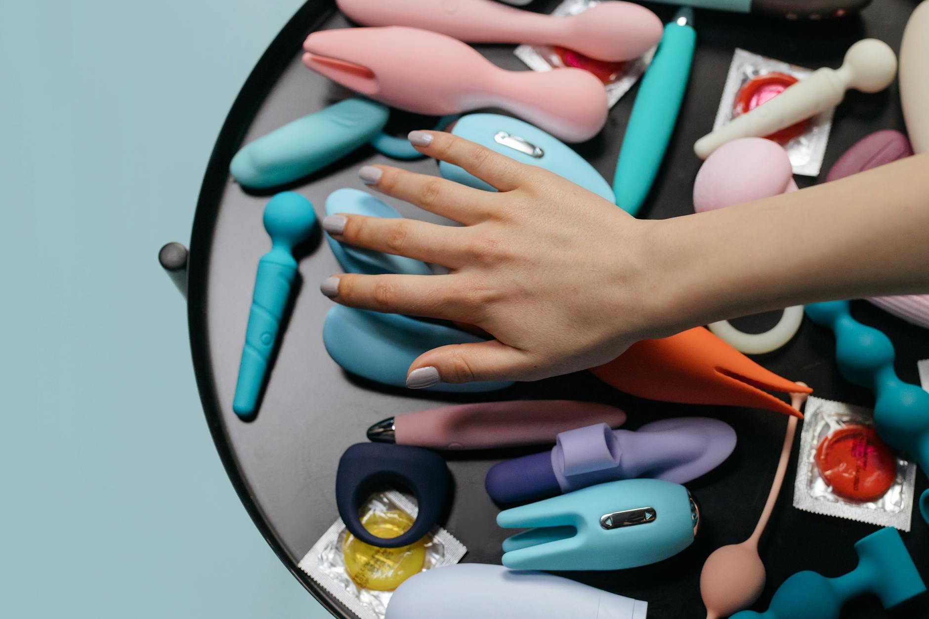 Close-up of hands holding a sleek blue vibrator against a purple background, representing intimate connection between partners.