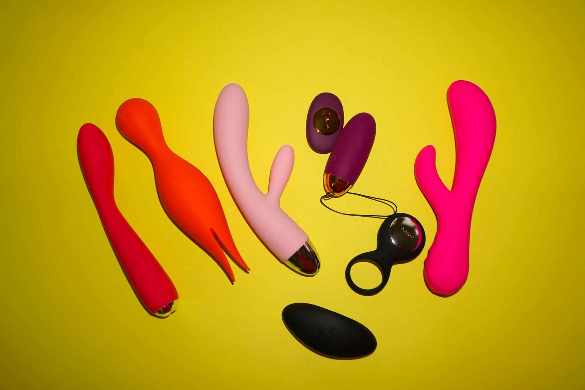 Colorful sex toys on a bright yellow background showcasing various designs and textures